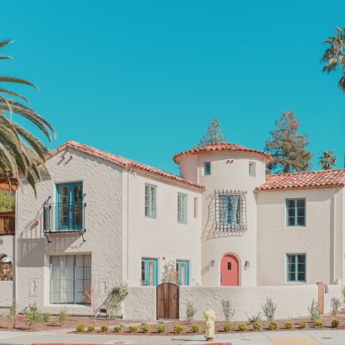 white and pink concrete building near palm trees under blue sky during daytime